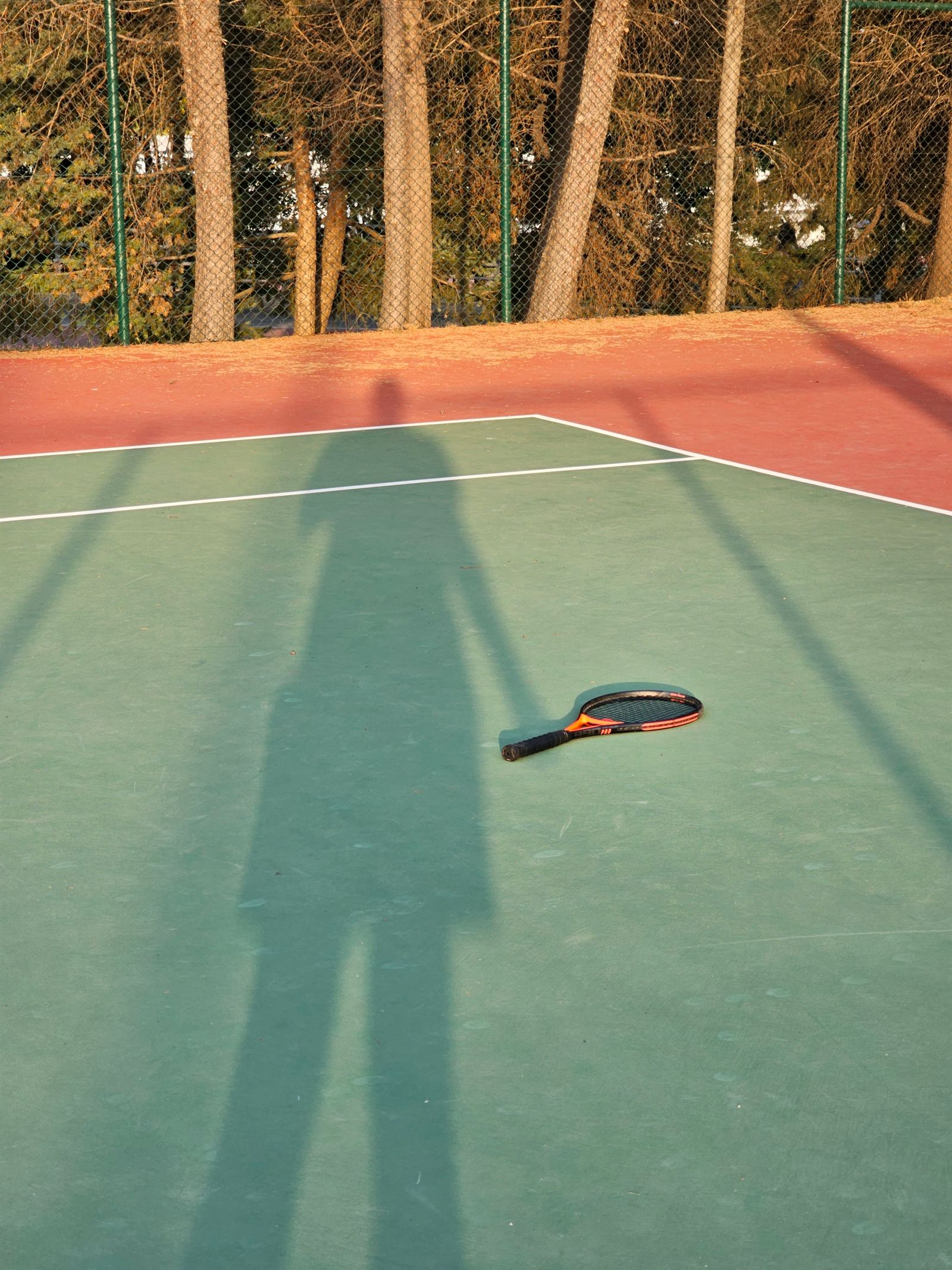 Tennis racket resting on a sunlit court